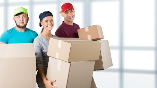 Removal team carrying furniture from a narrow staircase in a Lambeth property