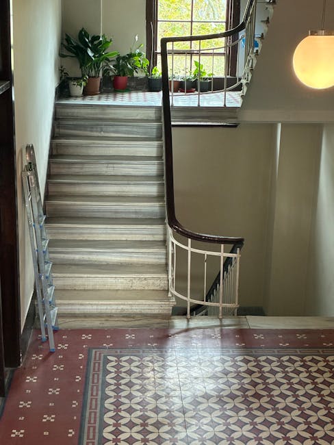 The image shows a staircase inside a residential property, with a marble or stone ramp providing stair access. The staircase features a dark wooden handrail and white balustrades, leading up to a smal